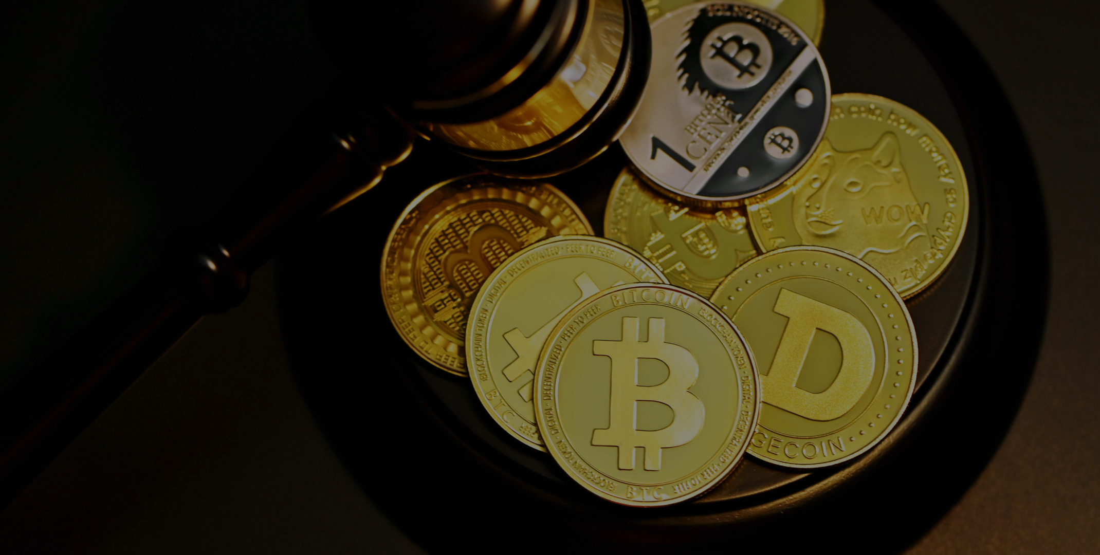 A collection of physical cryptocurrency coins including Bitcoin, Dogecoin, and other crypto tokens arranged on a dark surface next to a judge's gavel, symbolizing cryptocurrency regulation or legal proceedings